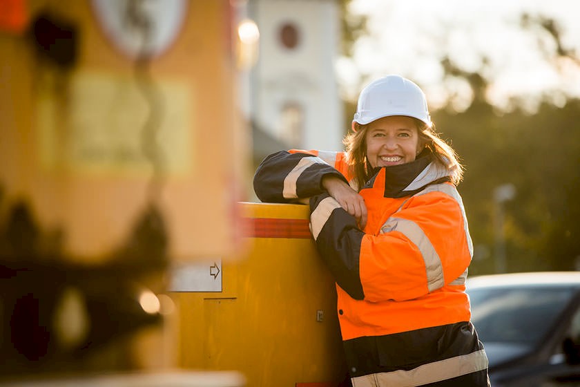 Brandschutz auf Baustellen: Bauarbeiterin mit Schutzkleidung lächelt auf der Baustelle
